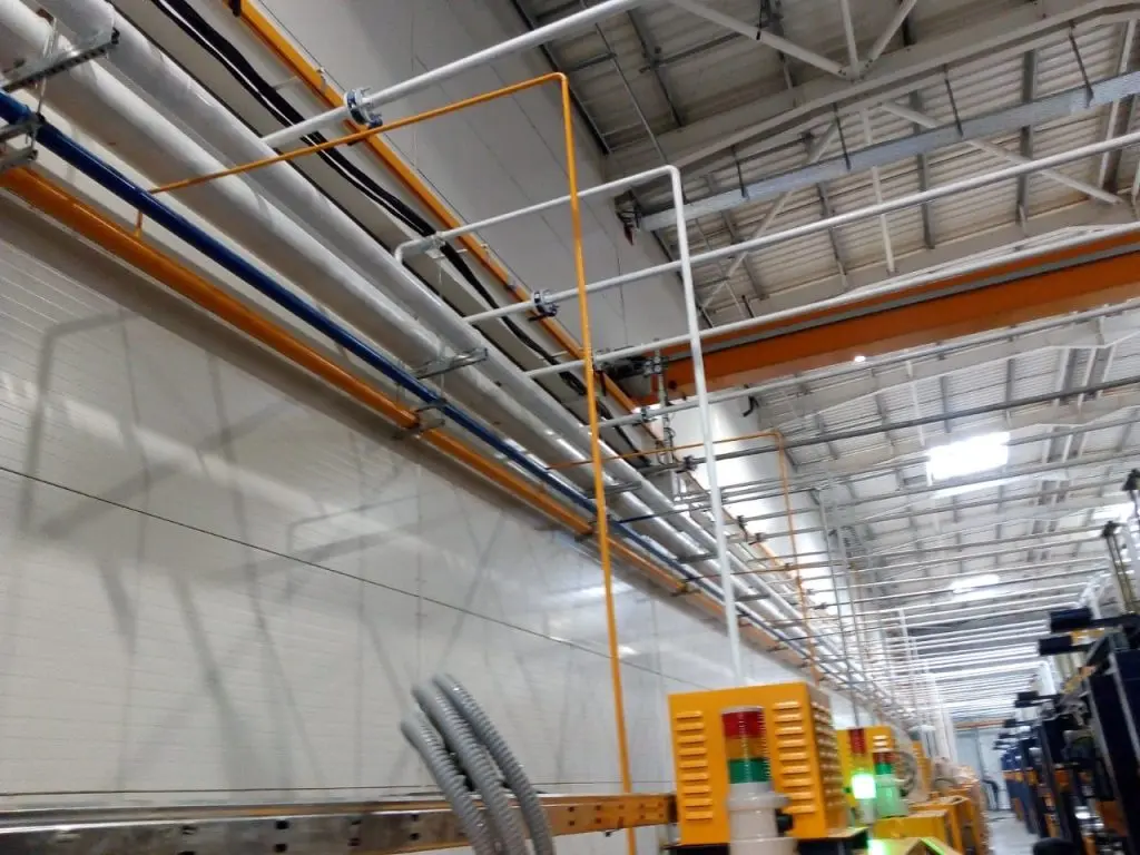 Atelier FPS Maroc à Mohammedia — réseau de tuyauteries gaz multicolores au plafond du hangar